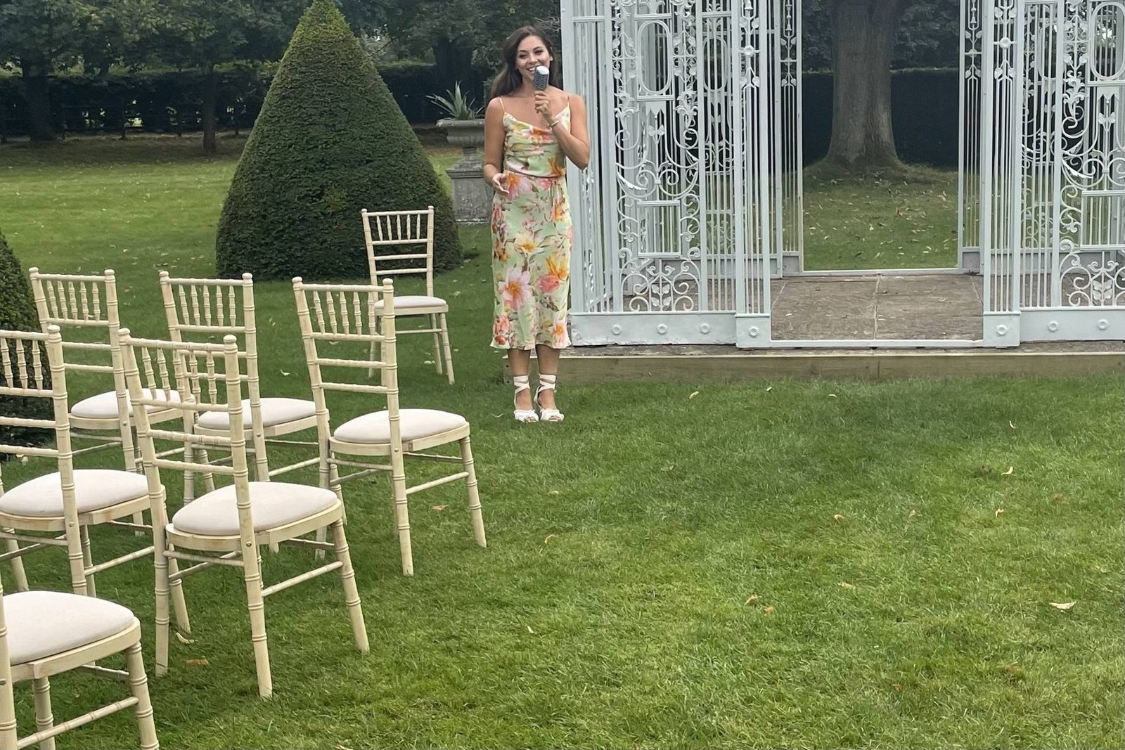 Melanie singing at an outdoor ceremony with a white gazebo
