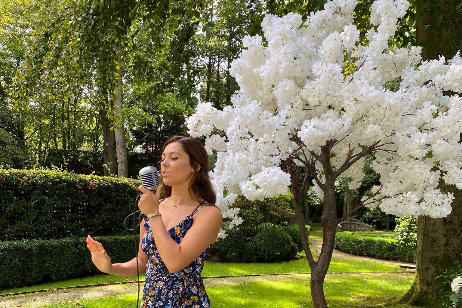 Melanie singing at an outdoor wedding ceremony beside a white blossom tree